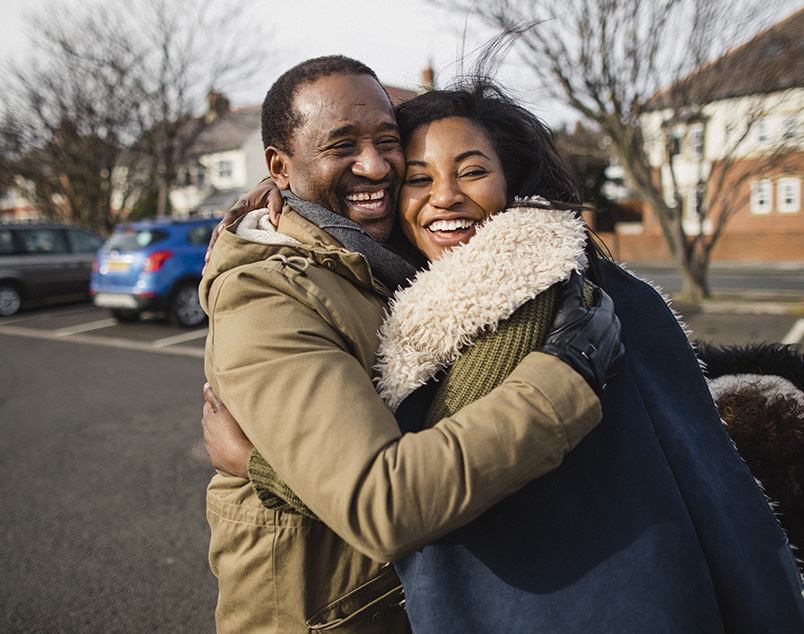 Photo of two adults embracing in a hug outdoors